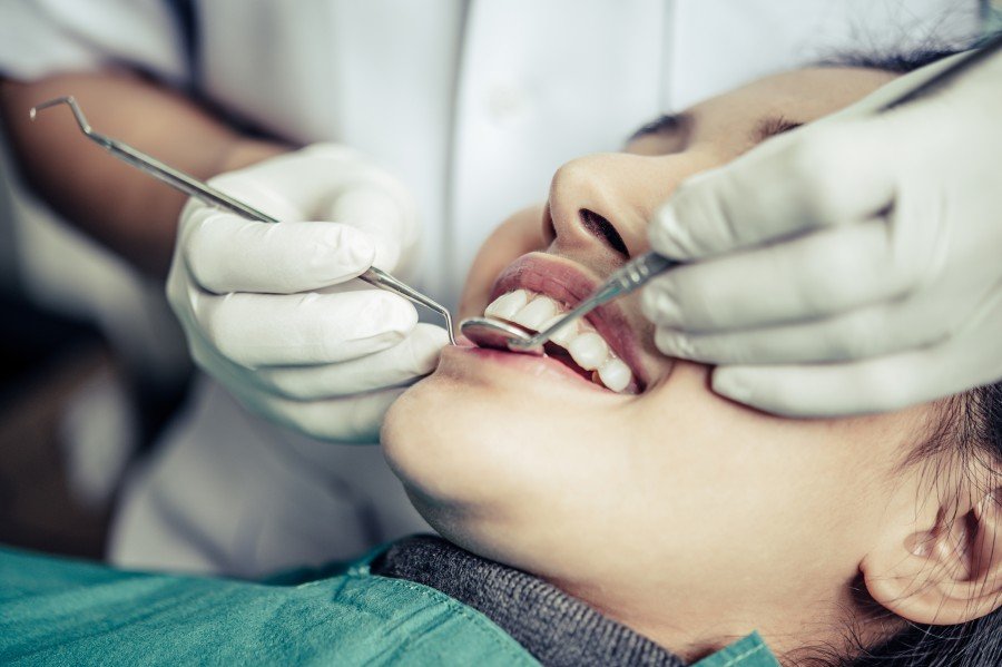 Dentist examining a patient’s teeth with dental instruments during a treatment.